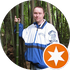 Person in a blue and white jacket with a logo in a forest setting