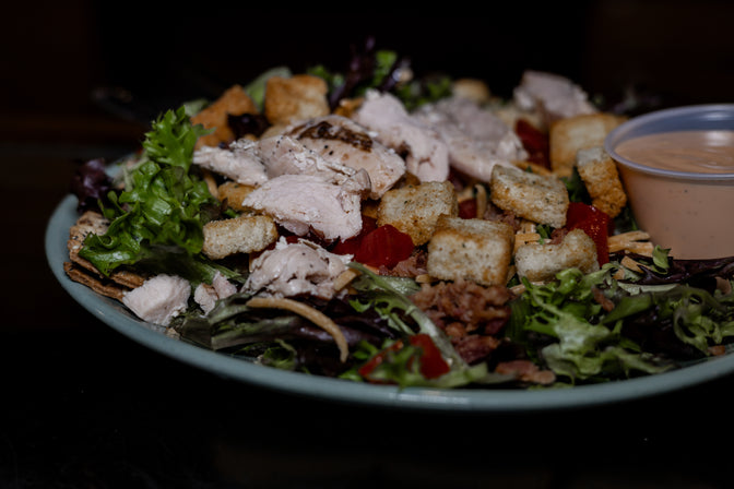 Salad with chicken, croutons, and dressing on a plate