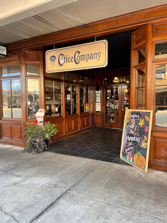 Front entrance of a coffee company with a sign and sidewalk.