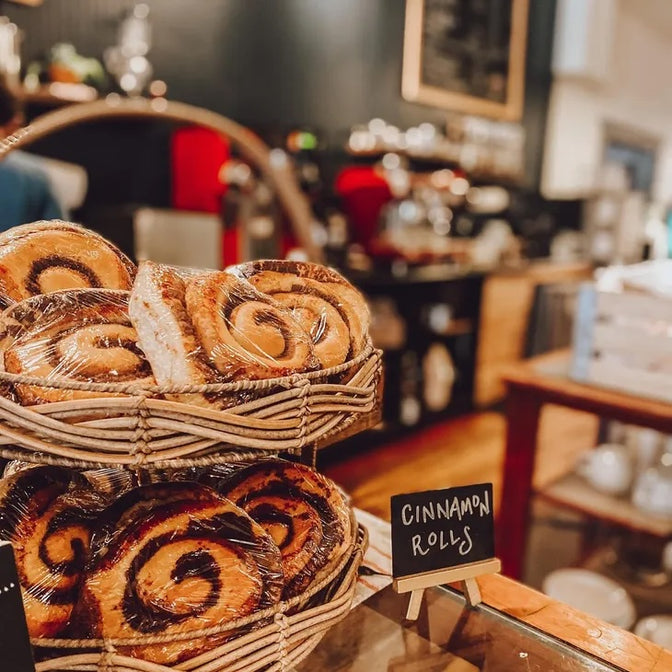 Baskets of cinnamon rolls on a counter with a blurred cafe background