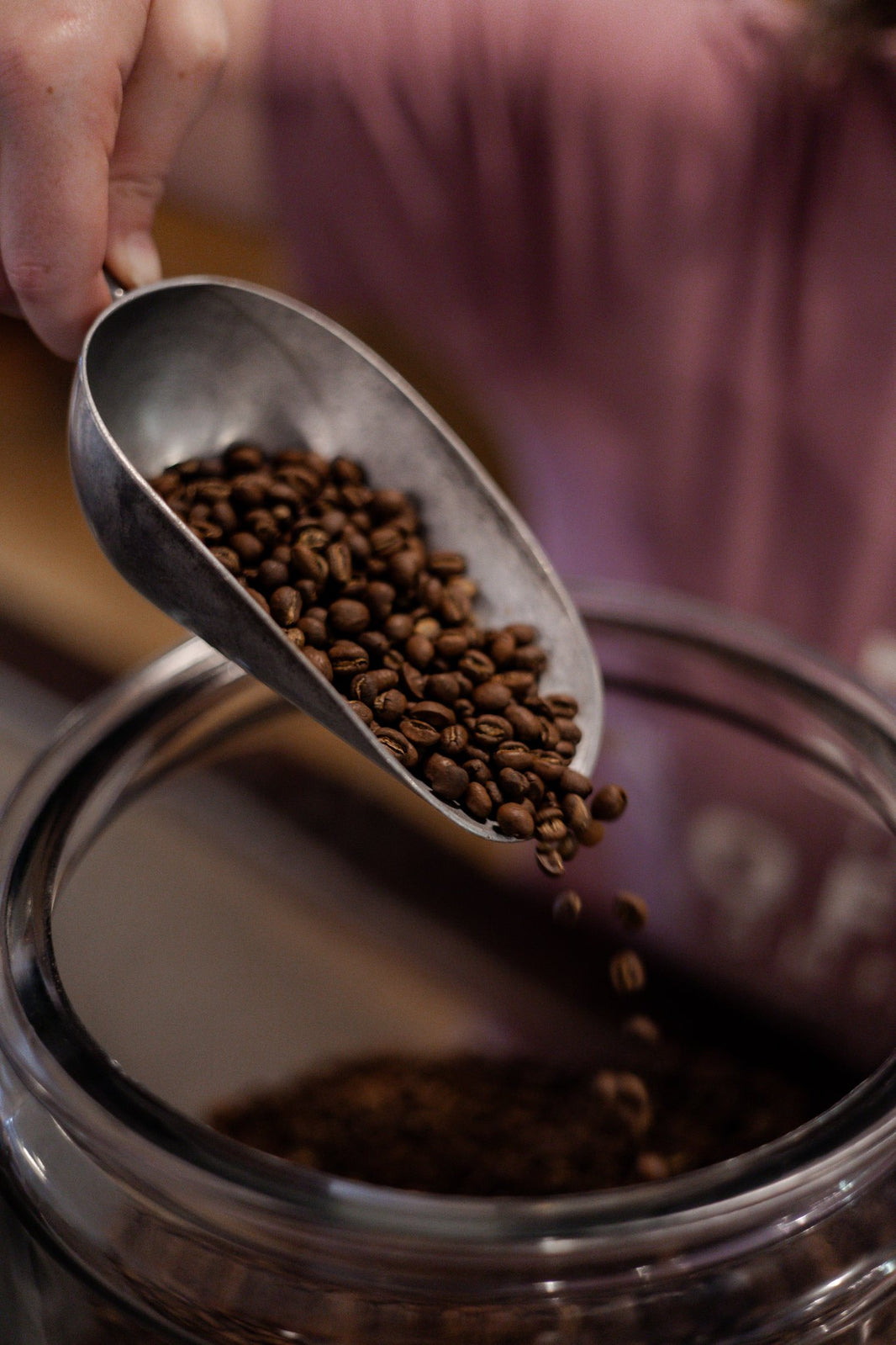 image Scoop of coffee beans being poured into a glass jar