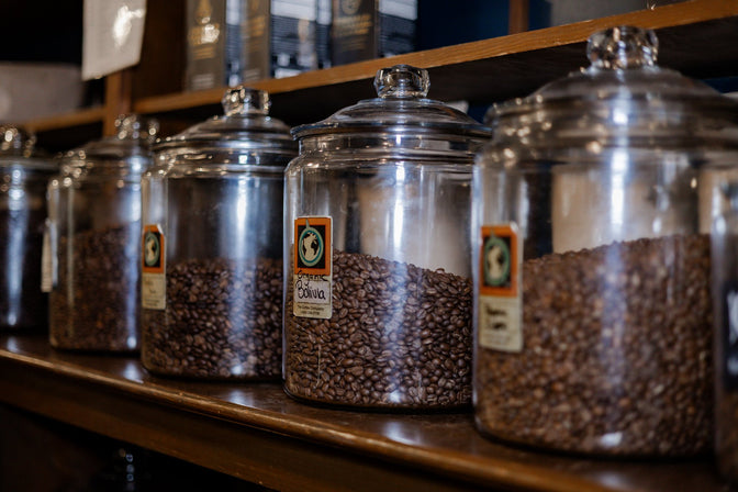 Glass jars filled with coffee beans on a wooden shelf