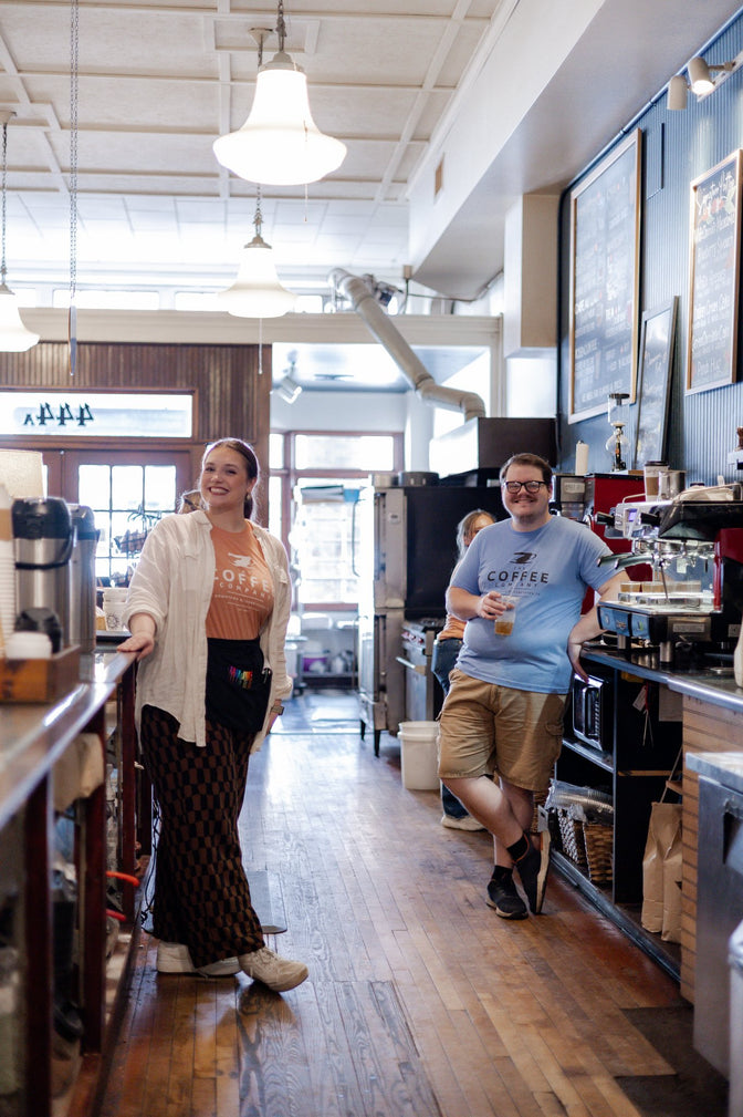 Two smiling team members standing behind the coffee station