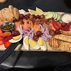 Platter of assorted meats, cheeses, fruits, and bread on a dark surface